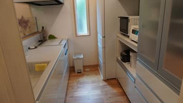 Una cocina compacta con microondas, un pequeño cubo de basura y una ventana.