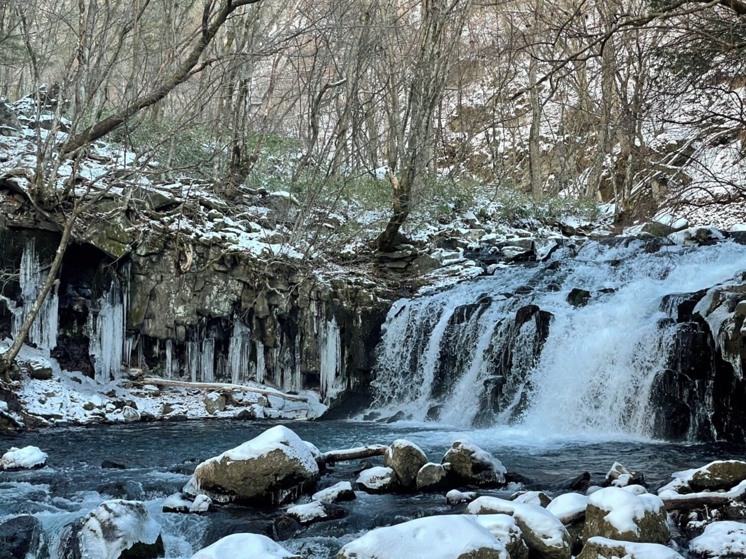 A waterfall surrounded by snow-covered rocks and trees.