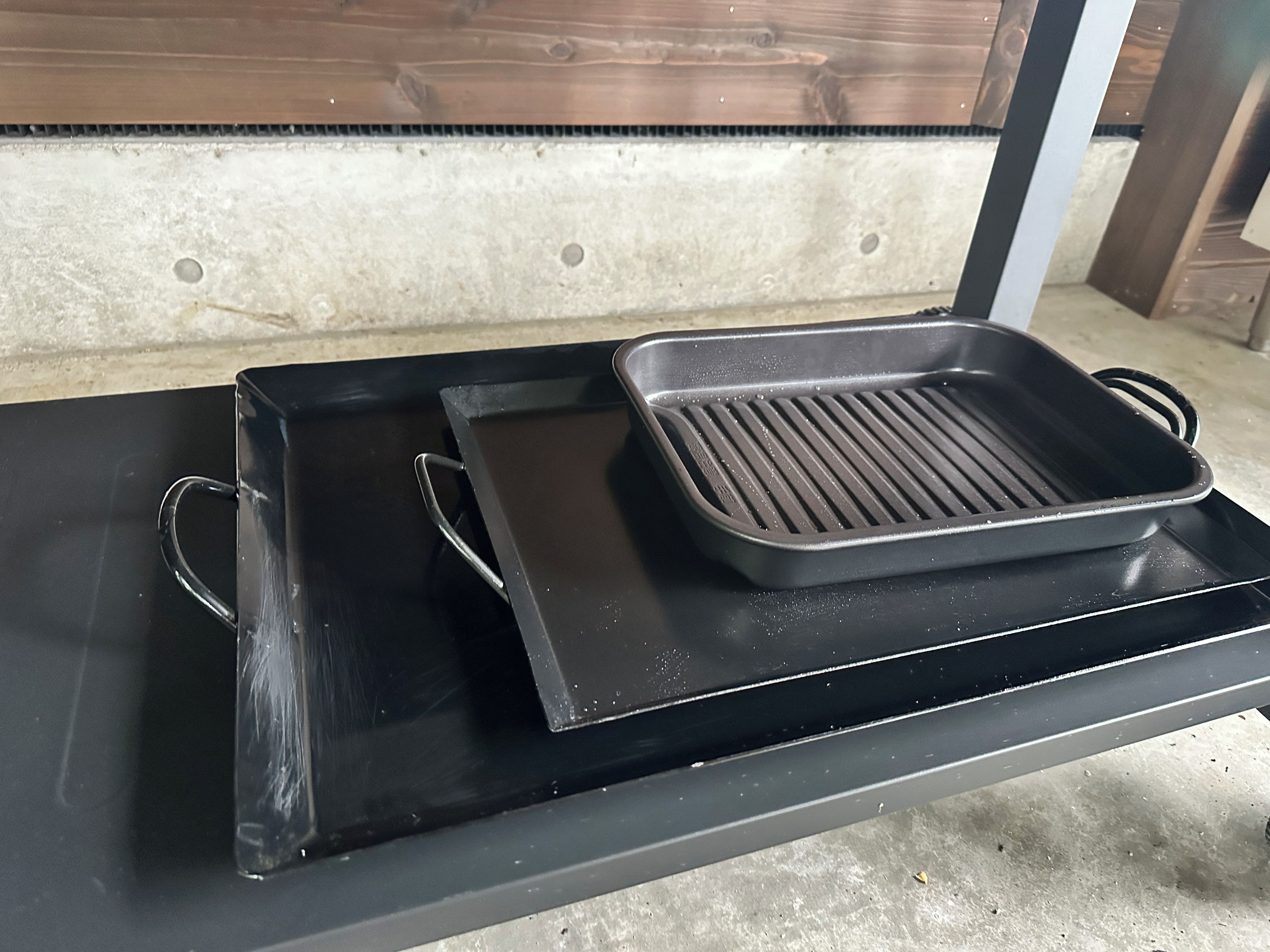 Una bandeja negra sobre una mesa con una plancha metálica encima.