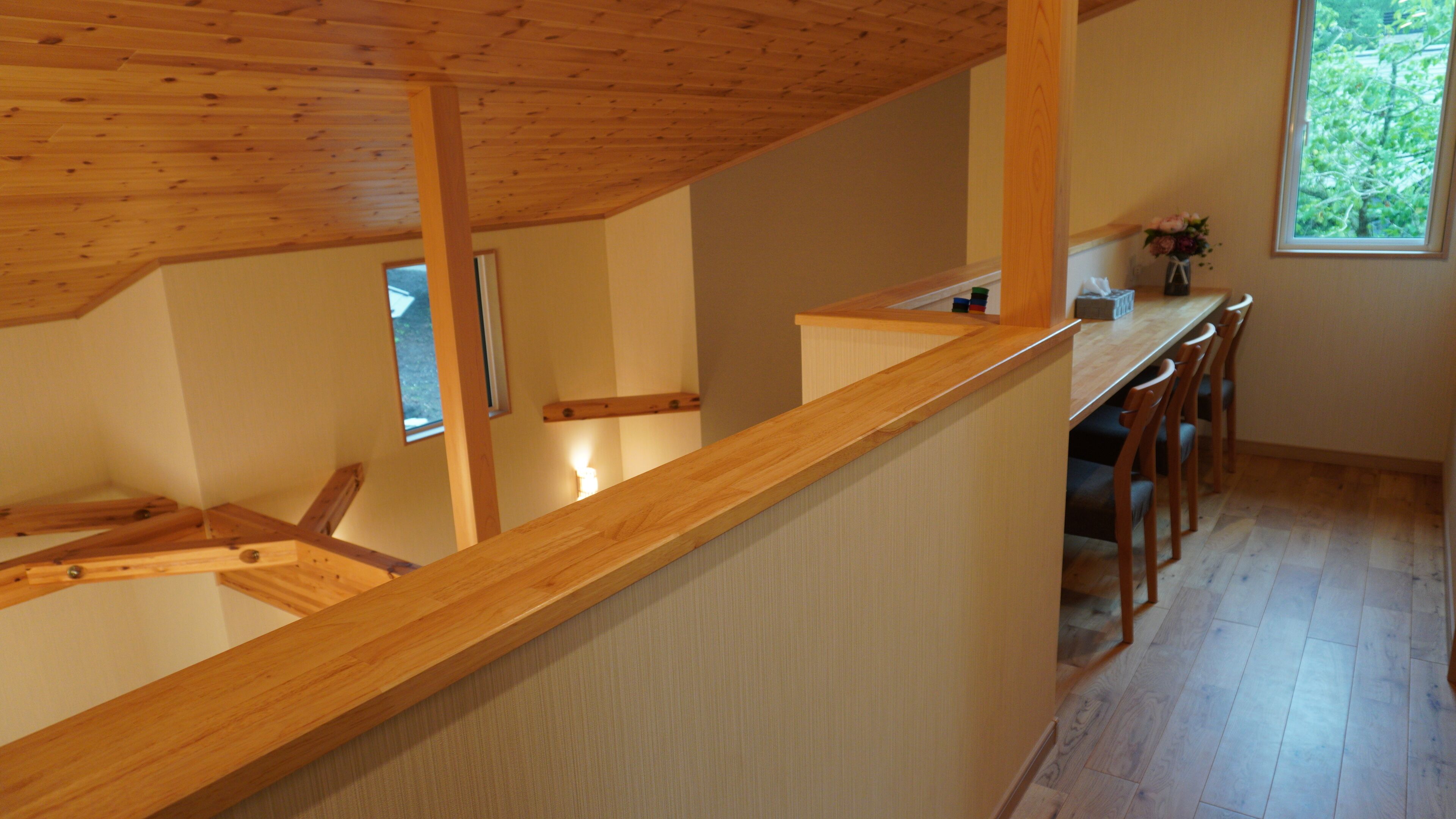 A wooden interior with a high ceiling, a kitchen area with a wooden countertop, and a view of greenery outside.