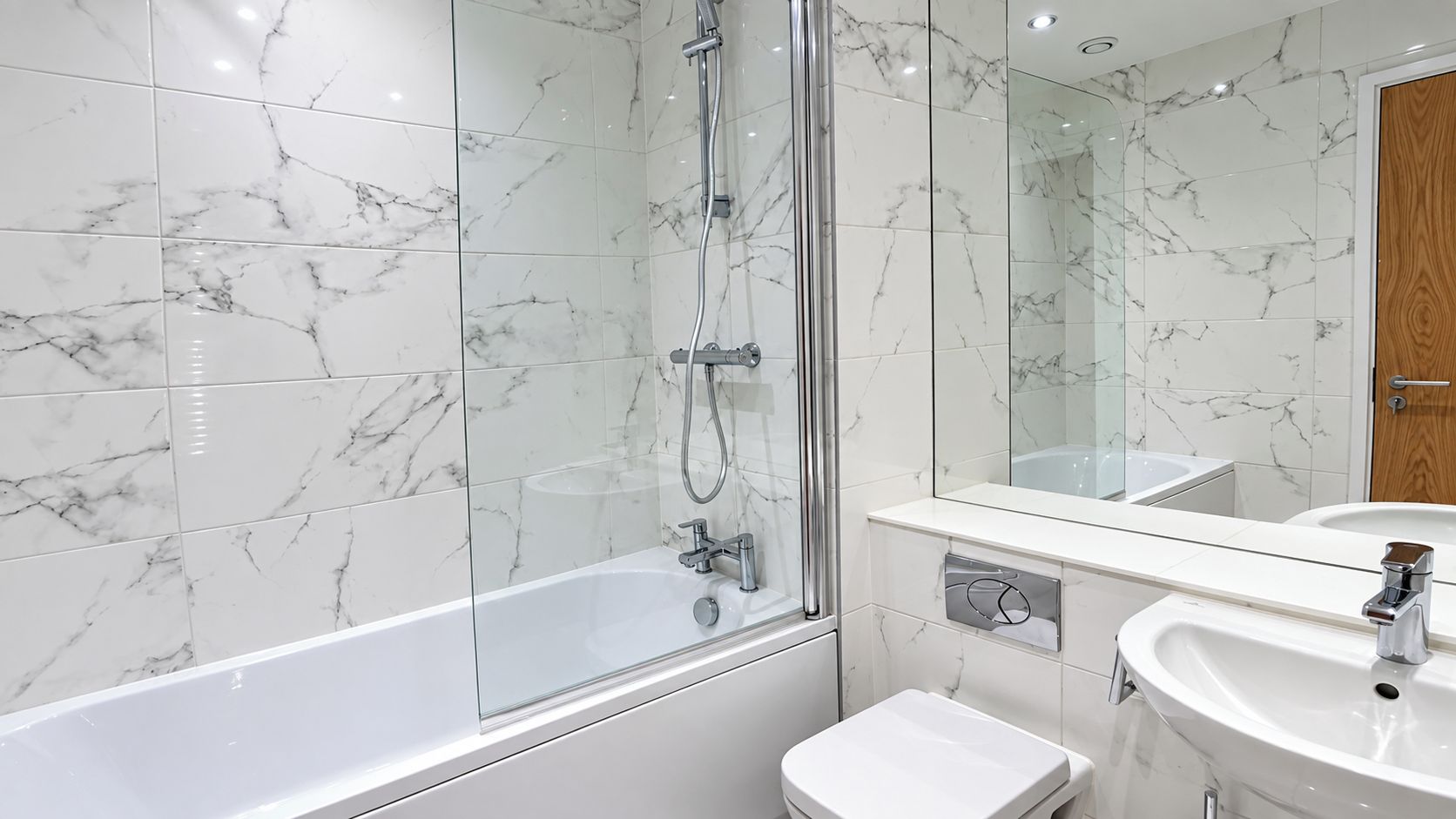 Une salle de bain moderne avec une douche à parois de verre, un lavabo blanc et une porte en bois.