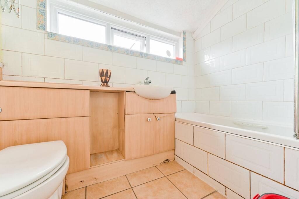 Ein Badezimmer mit Toilette, Holzschränken, einem Waschbecken und einer Badewanne.