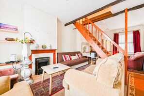 Una sala de estar con chimenea, un sofá, una mesa de centro y una escalera.
