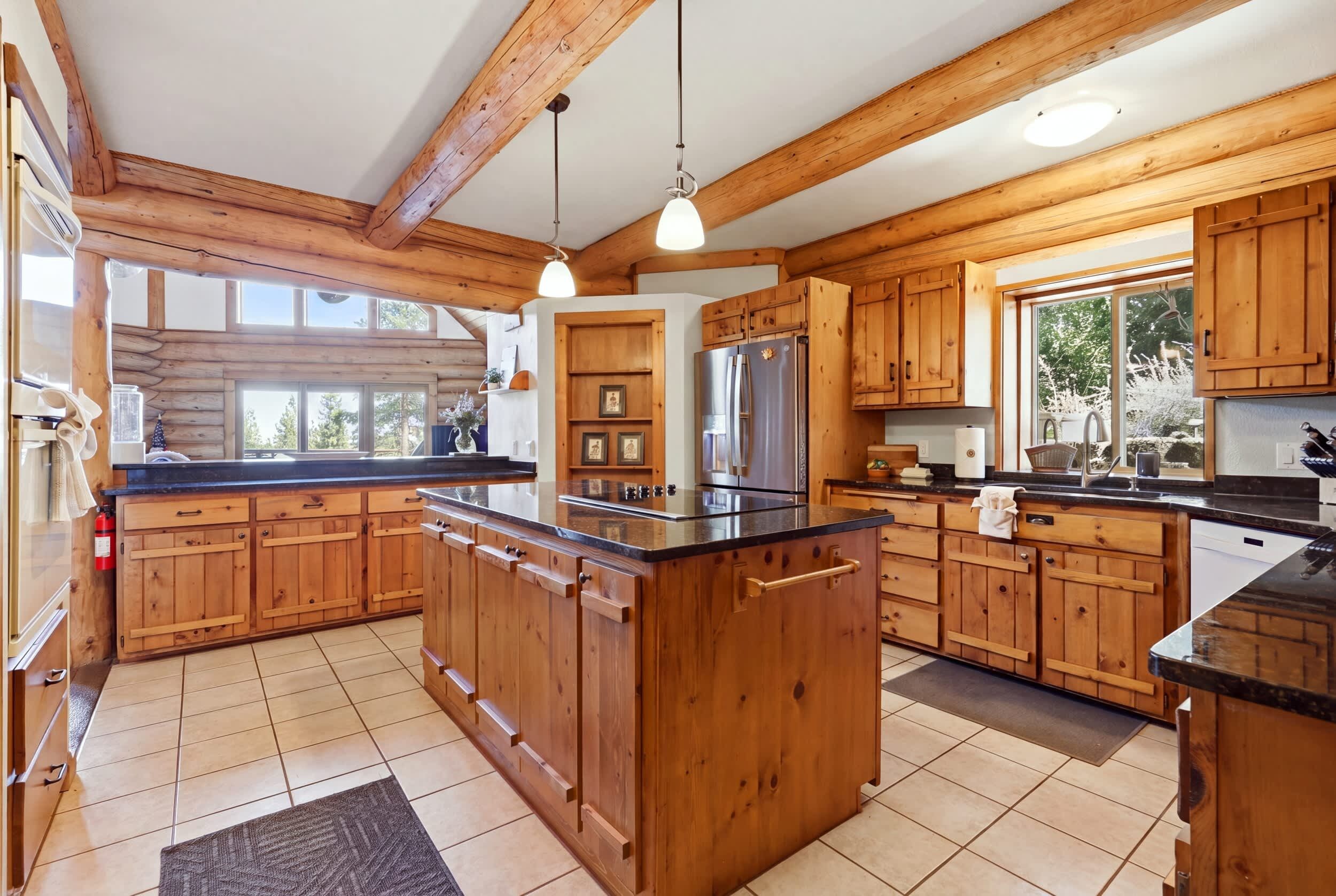 A spacious kitchen with wooden cabinets, a central island, and a large window providing natural light.
