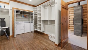 Un cuarto de lavandería con lavadora, secadora y estanterías.
