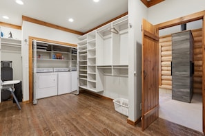 A laundry room with a washing machine, dryer, and storage shelves. - Cozy's Lakefront Lodge | Luxury Log Cabin (Harrison)