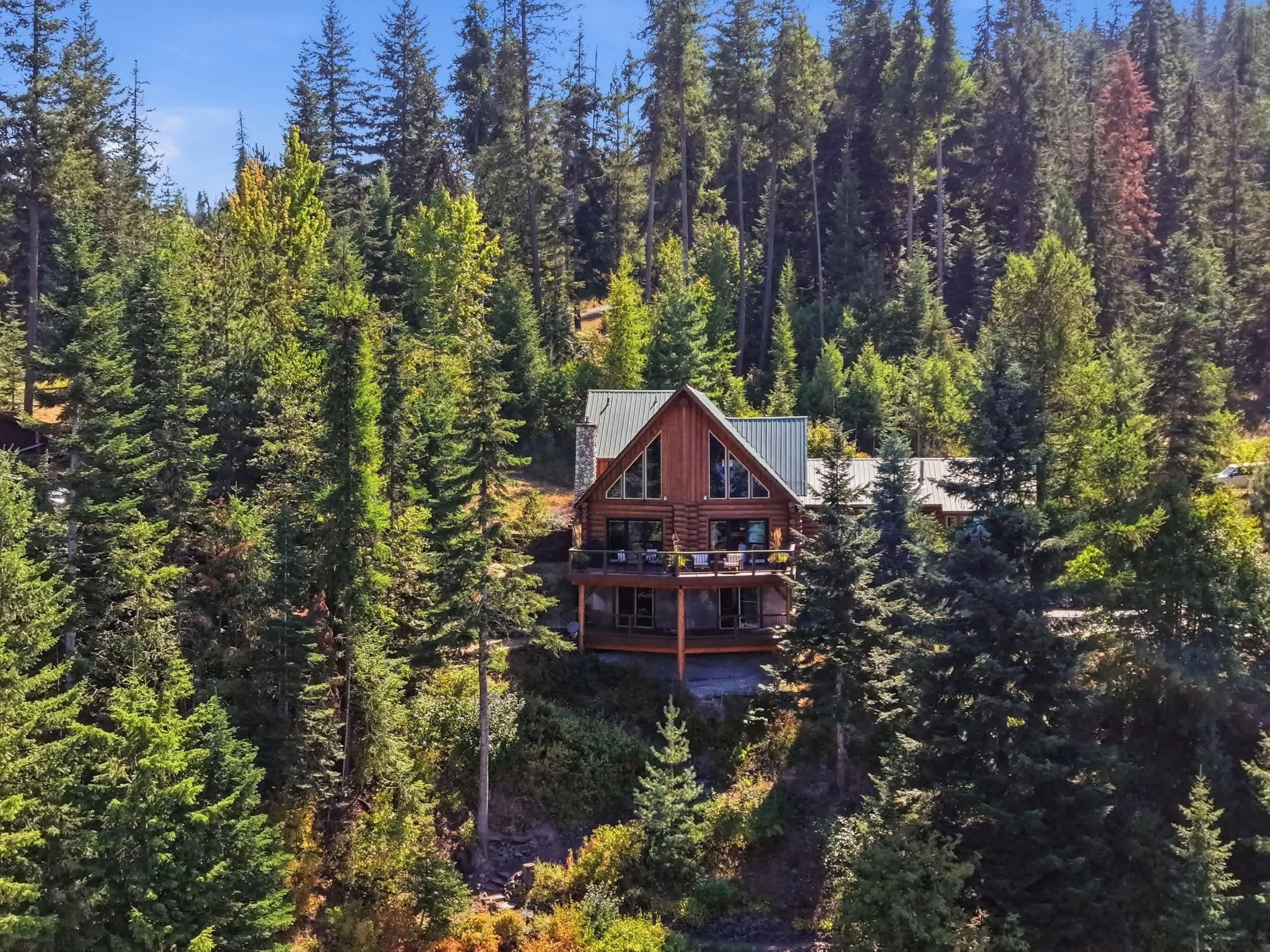 Eine Blockhütte mit einem Balkon, umgeben von dichtem Wald.