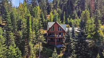 Eine Blockhütte mit einem Balkon, umgeben von dichtem Wald.