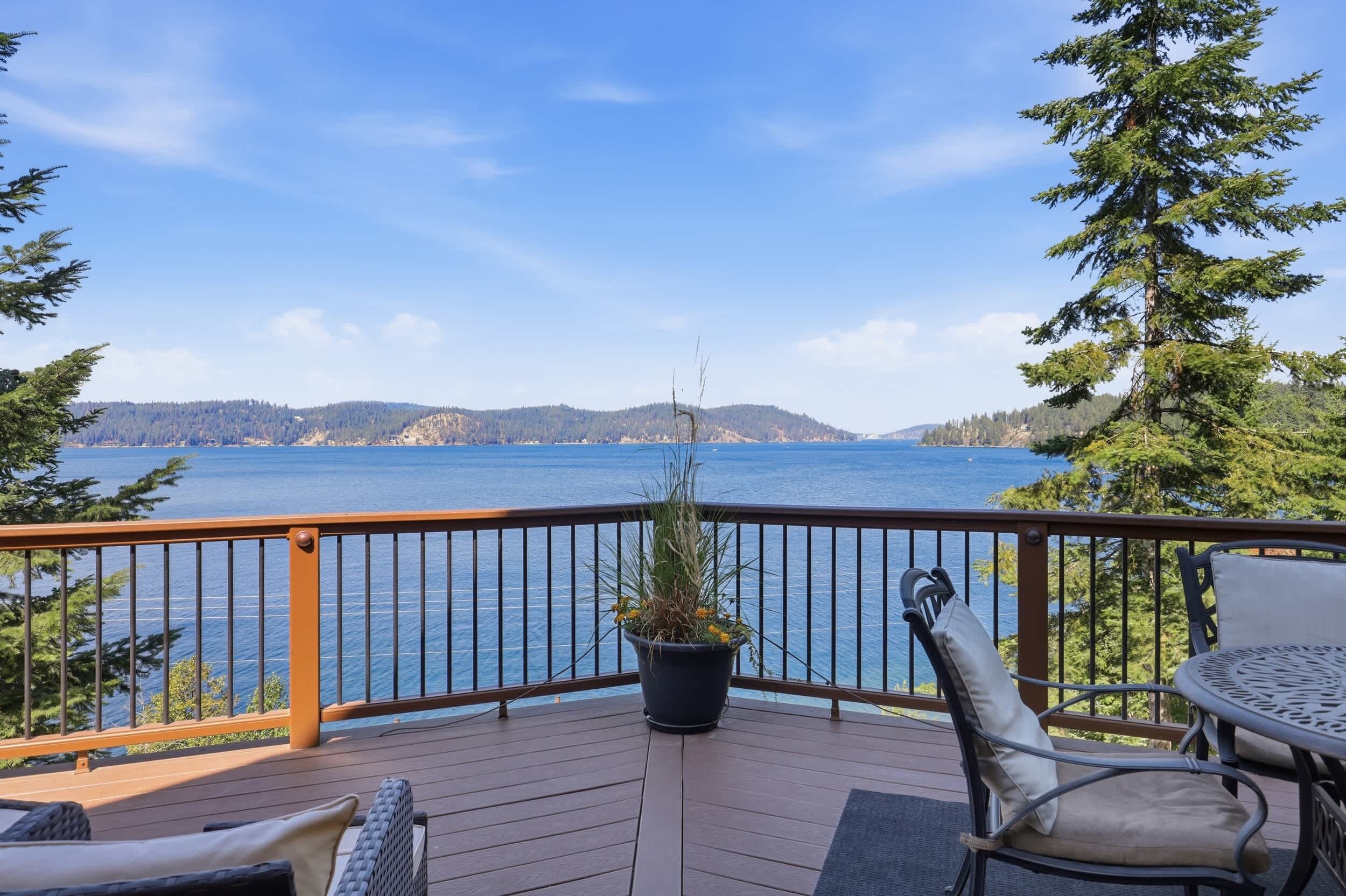 Una terraza con vista a un lago, una planta en maceta y mobiliario exterior.