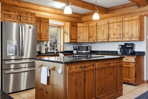 Una cocina con armarios de madera, electrodomésticos de acero inoxidable y una isla grande.