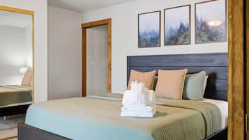 Ein Hotelzimmer mit einem Bett, einem Holz-Kopfteil, einem Spiegel und drei gerahmten Bildern an der Wand.