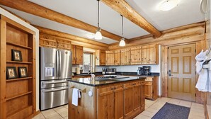 Una cocina con gabinetes de madera, un refrigerador de acero inoxidable, un microondas y una cafetera.