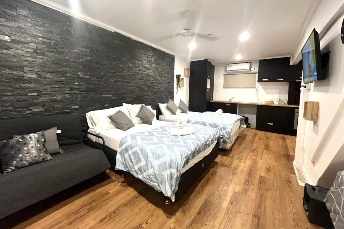 A bedroom with a bed, a sofa, a desk, and a TV.