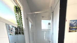 Un bagno con doccia, lavabo e specchio.