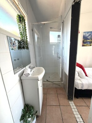 Un baño con ducha, lavamanos y espejo.