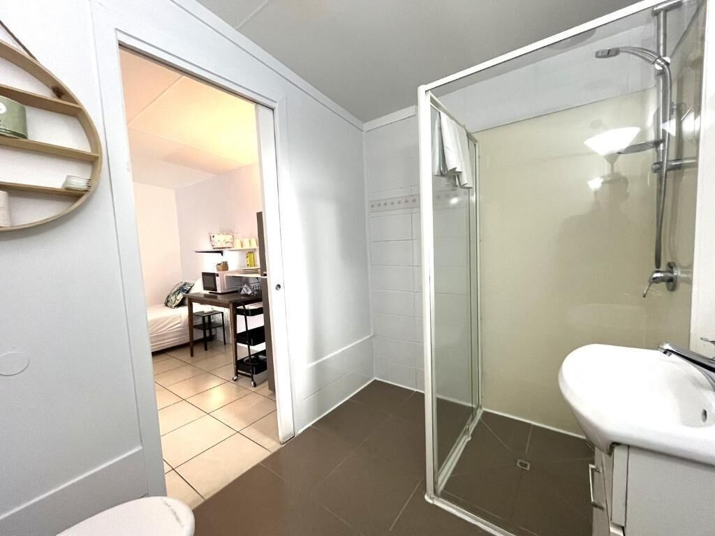 A bathroom with a glass shower enclosure, a white sink, and a toilet.