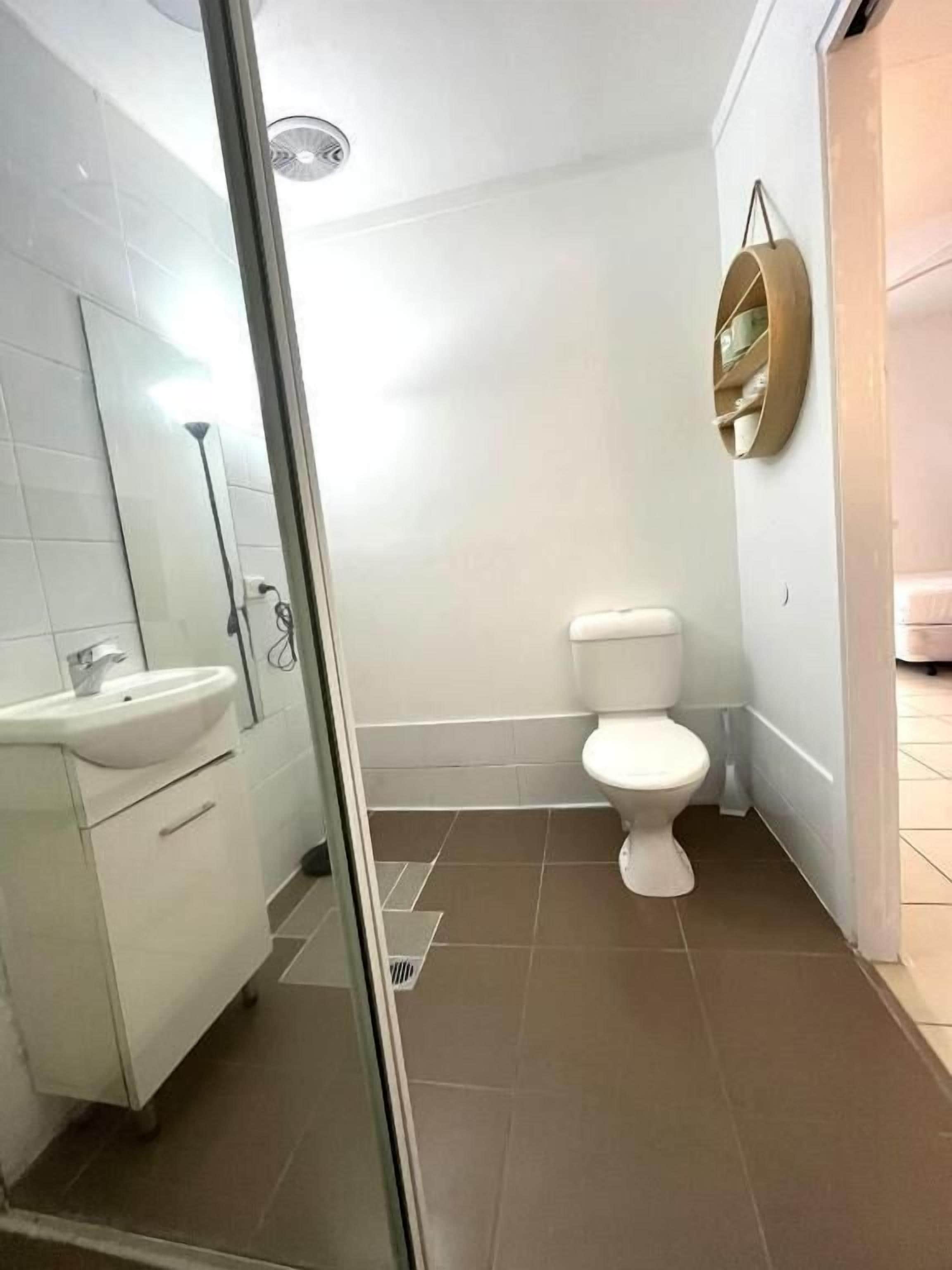 A bathroom with a toilet, sink, and mirror.