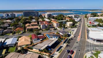 An aerial view of a coastal town with a main road, buildings, and a beach in the background.