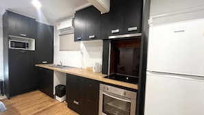 Una cucina moderna con mobili scuri, forno integrato e microonde.