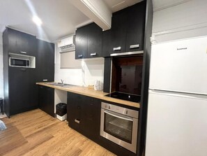 Una cocina moderna con armarios oscuros, horno empotrado y microondas.