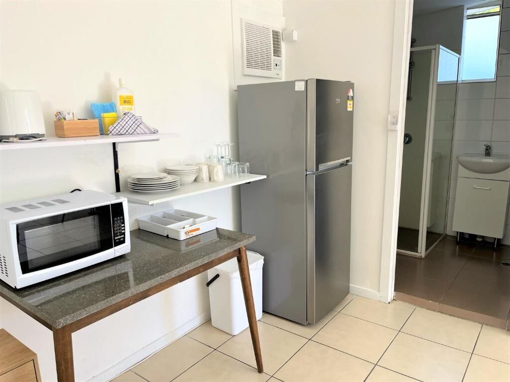 A compact kitchen with a microwave, a stainless steel refrigerator, and a small countertop.