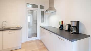 A modern kitchen with a built-in oven, a coffee maker, and a kettle.