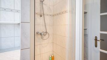 A bathroom with a shower, tiled walls, and a door with a handle.