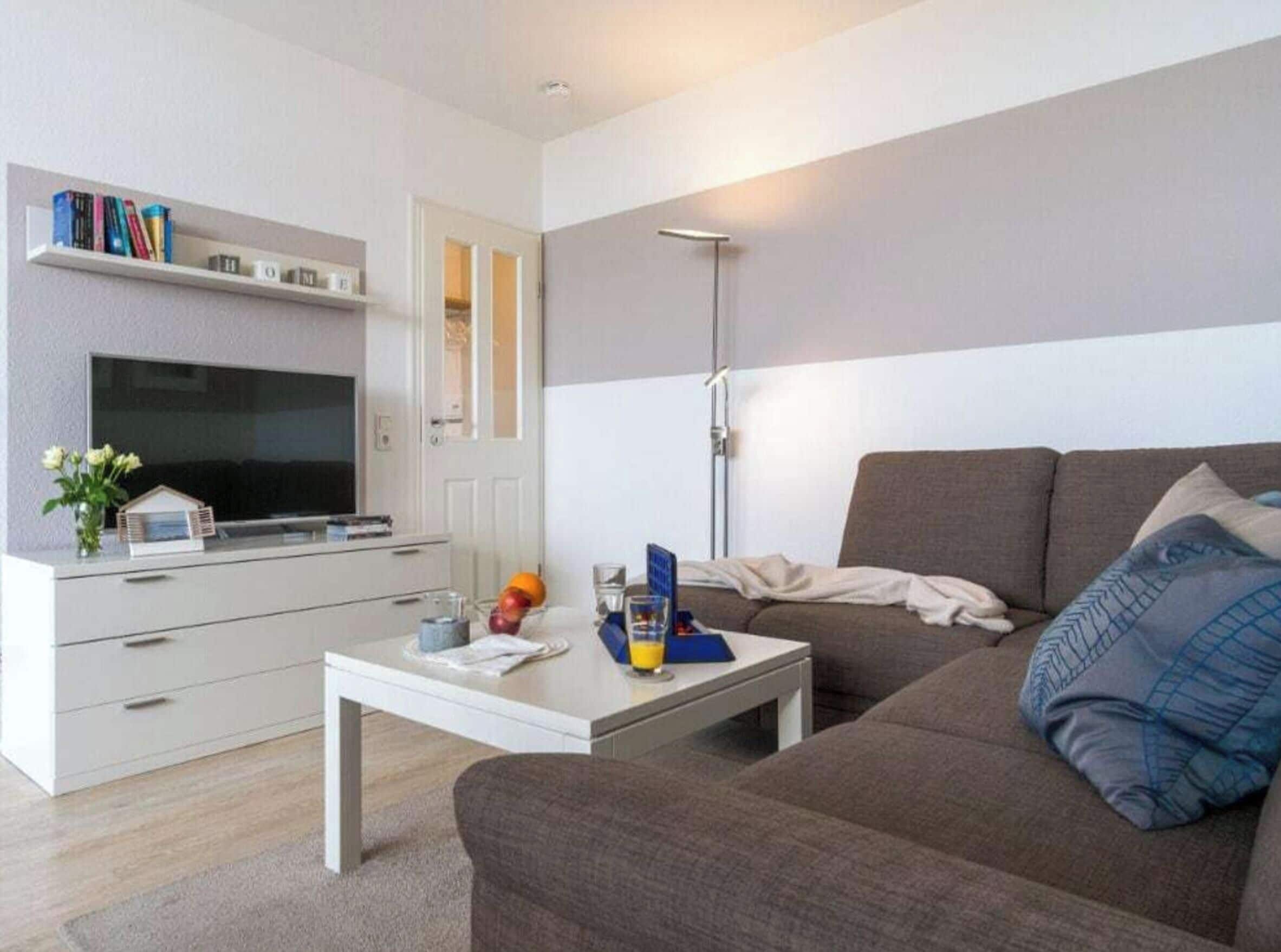 Een moderne woonkamer met een flatscreen televisie, een bank, een salontafel en een boekenkast.