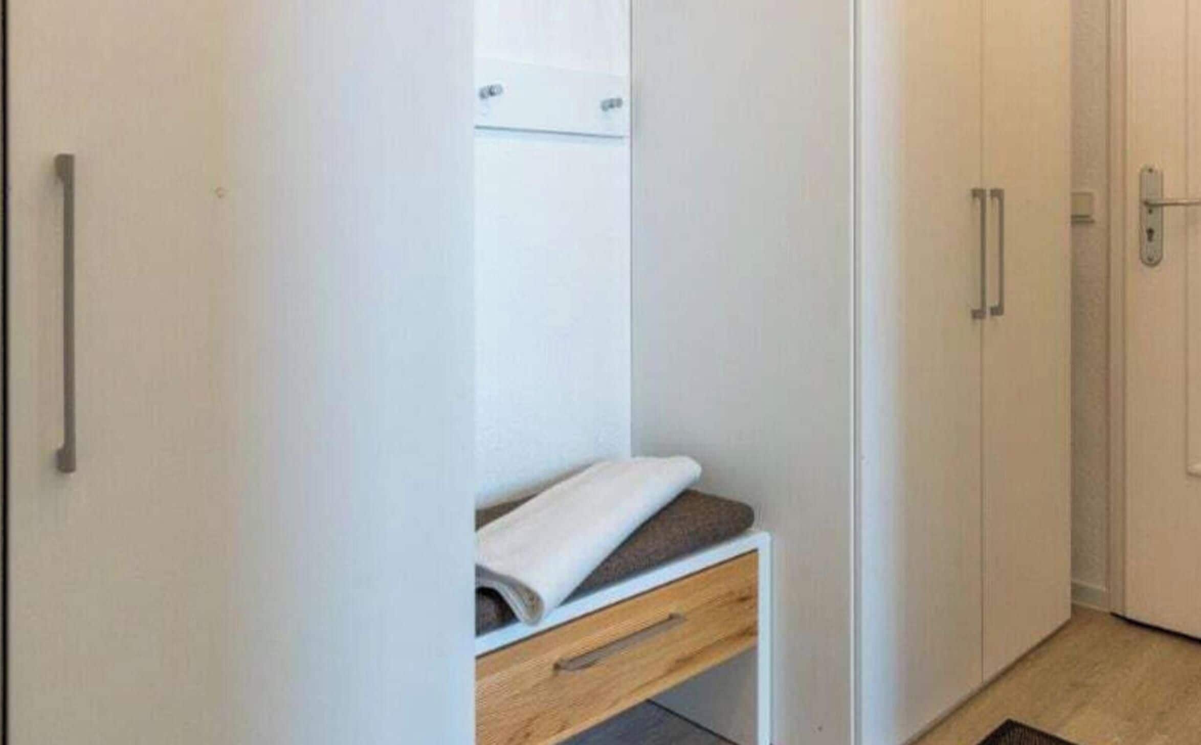 Un armario blanco con un cajón de madera y espacio para colgar.