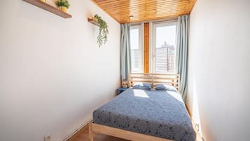 Um quarto com teto de madeira, uma cama com colcha estampada, duas mesas de cabeceira e uma janela com cortinas.