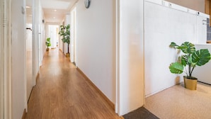 A hallway with wooden flooring, white walls, and a potted plant. - 3-bedroom Apartment Ideal for Families (Antwerp)