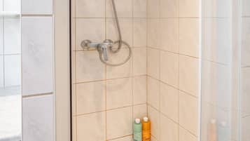 A walk-in shower with a glass door, a handheld showerhead, and a handheld shower attachment.