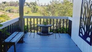 Une terrasse en bois avec une table et des chaises, donnant sur un paysage verdoyant.