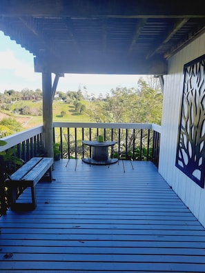 A wooden deck with a table and chairs, overlooking a green landscape.