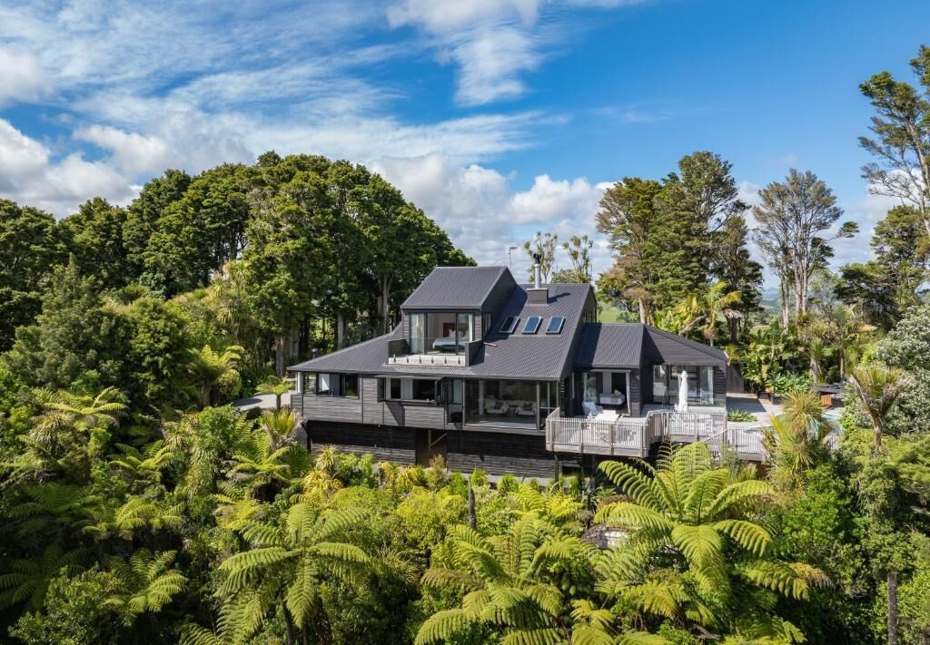 Una casa moderna de dos pisos rodeada de vegetación exuberante.
