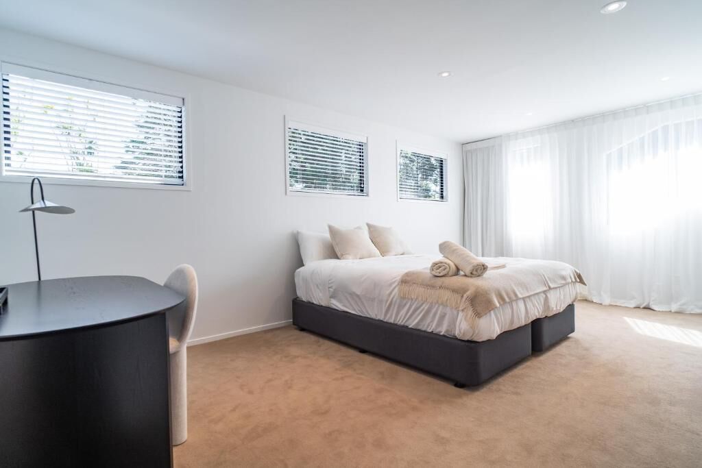 A bedroom with a bed, a desk, and a chair.