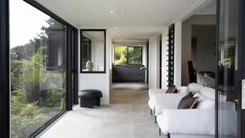 A modern interior with a sofa set, a glass partition, and a view of the outdoors.