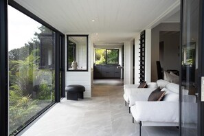 Ein modernes Interieur mit einer Sofagarnitur, einer Glastrennwand und Blick ins Freie.