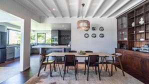 Una cocina moderna con una isla central, armarios de madera y un comedor con alfombra y sillas.
