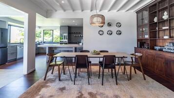 A modern kitchen with a central island, wooden cabinets, and a dining area with a rug and chairs.