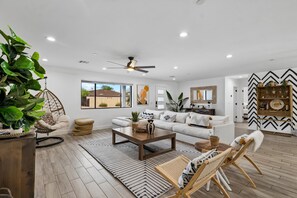 A spacious living room with a sofa, coffee table, and a hanging chair. - The ONE | Pool, Game Room, & Putting Green | Old Town Scottsdale | Sleeps 10 (Scottsdale)