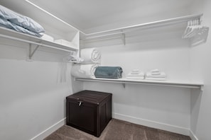 A laundry room with white shelves, a dark storage unit, and a carpeted floor. - The ONE | Pool, Game Room, & Putting Green | Old Town Scottsdale | Sleeps 10 (Scottsdale)