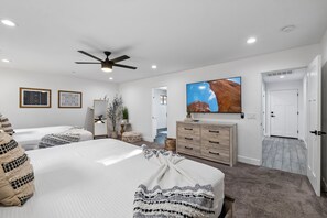 A bedroom with two beds, a ceiling fan, a TV, and a large window. - The ONE | Pool, Game Room, & Putting Green | Old Town Scottsdale | Sleeps 10 (Scottsdale)