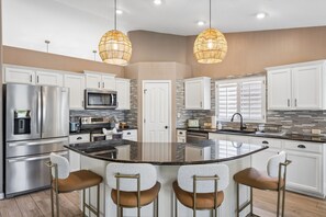 A modern kitchen with a central island, stainless steel appliances, and pendant lighting.