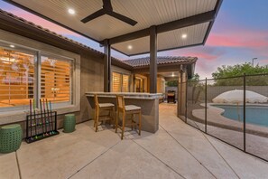 Un patio al aire libre con piscina, bar y zona de estar.