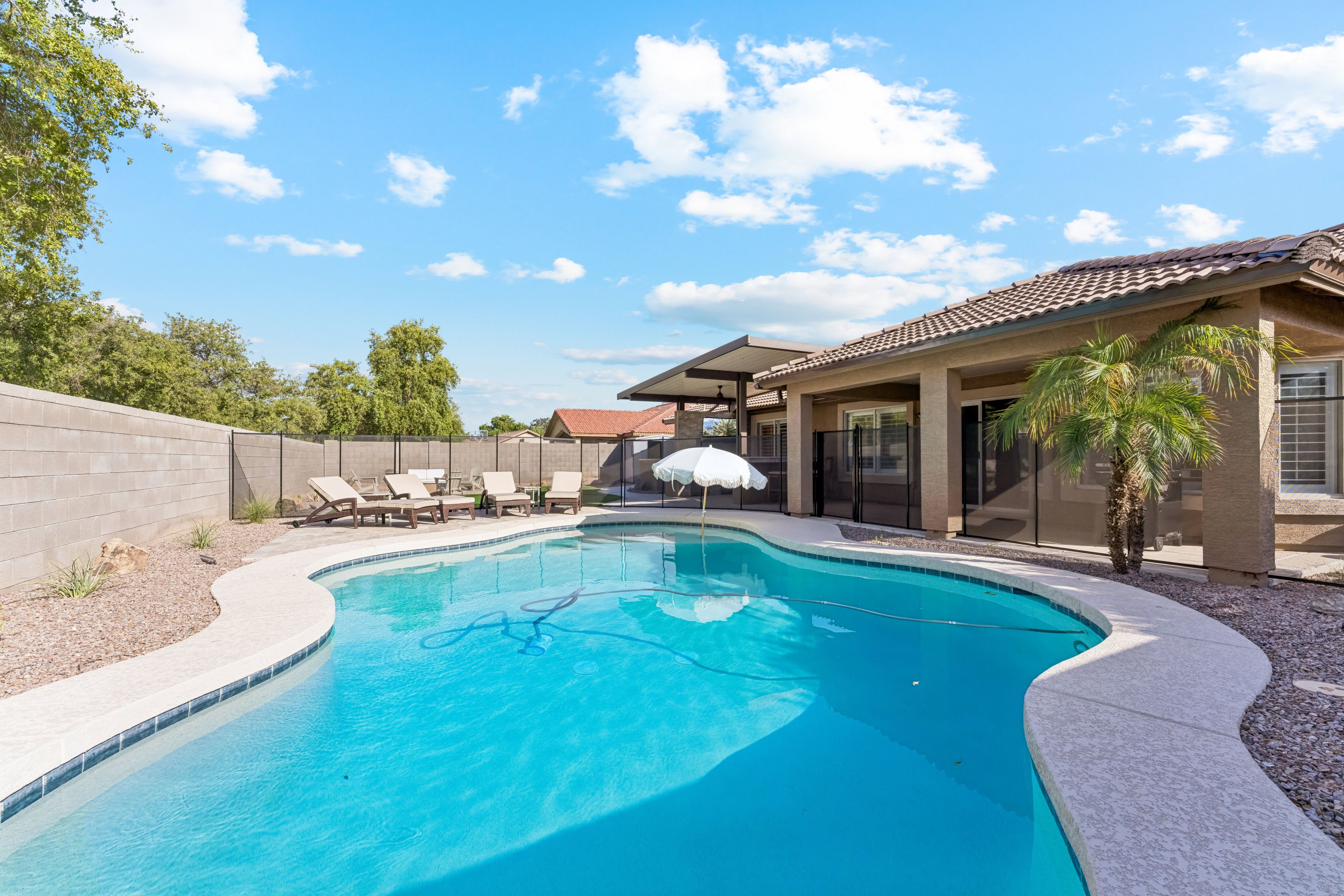 A swimming pool with lounge chairs and a covered patio area.