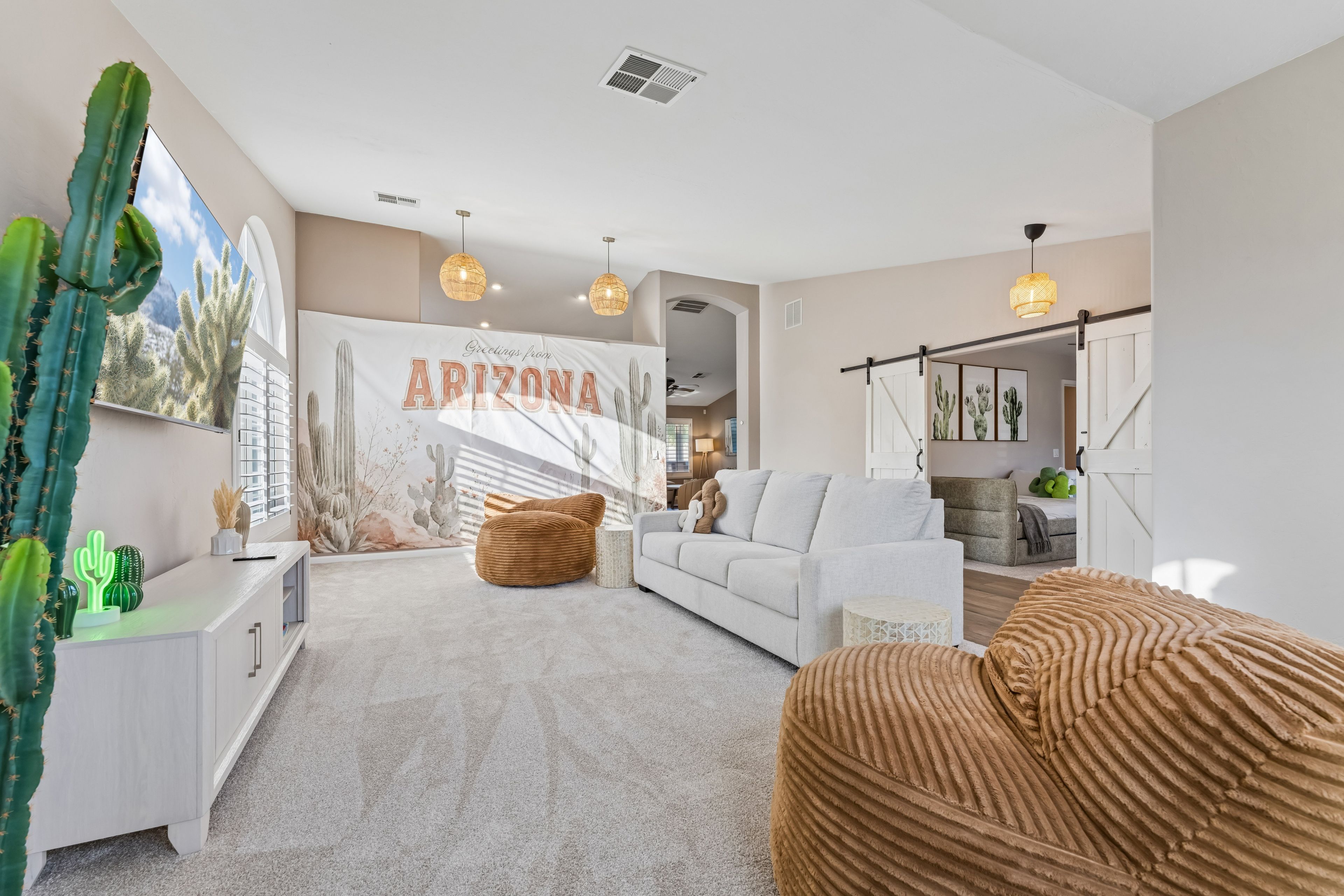 A spacious living room with a large wall mural, a sofa, a coffee table, and a cactus plant.