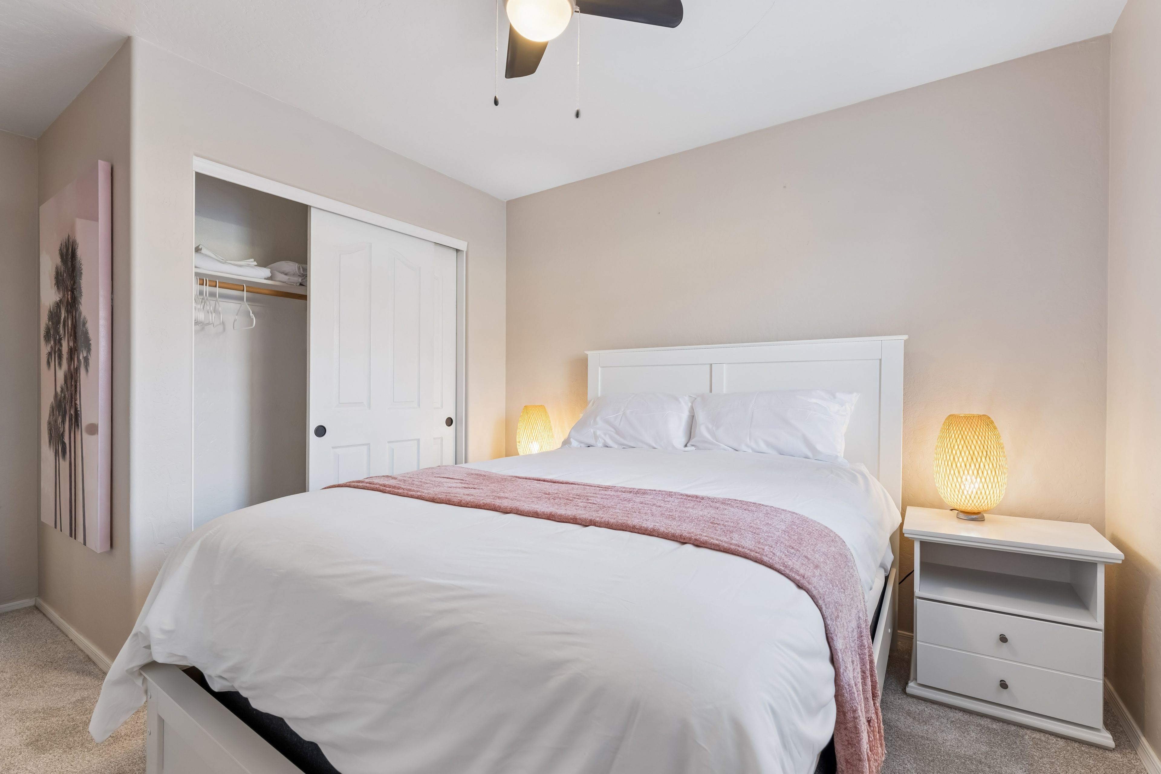 Een slaapkamer met een bed, nachtlampjes, een kledingkast en een deur.