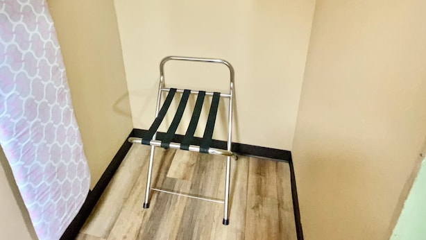 Ein kleines Zimmer mit Holzboden, einem Metalltrockner und einem Handtuch an der Wand.