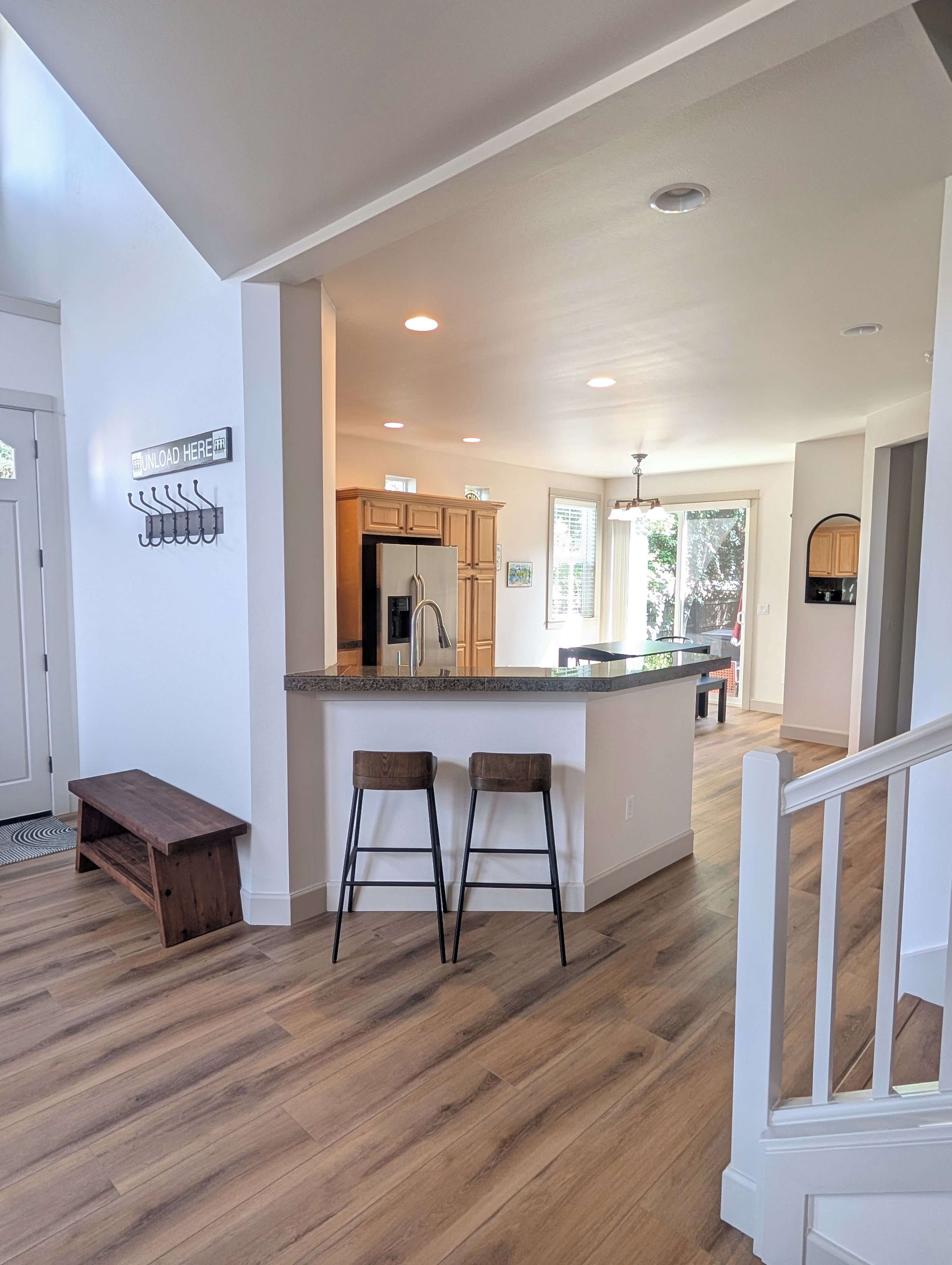 A modern kitchen with a central island, wooden flooring, and a bench.